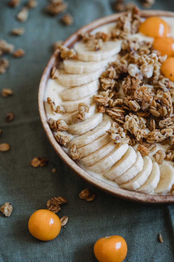 A nutritious breakfast bowl featuring bananas, granola, and yellow plums, perfect for a healthy start.